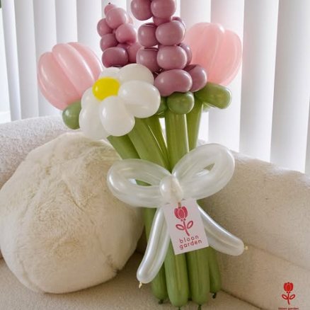 Mauve and blush lavender spikes and tulips resting on a cream cushion.