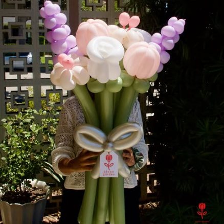 White and blush balloon roses with lilac spikes, held outdoors at dusk.