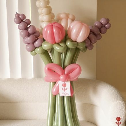 A balloon bouquet of pink tulips and mauve hyacinth on long sage stems, tied with a pink balloon bow.